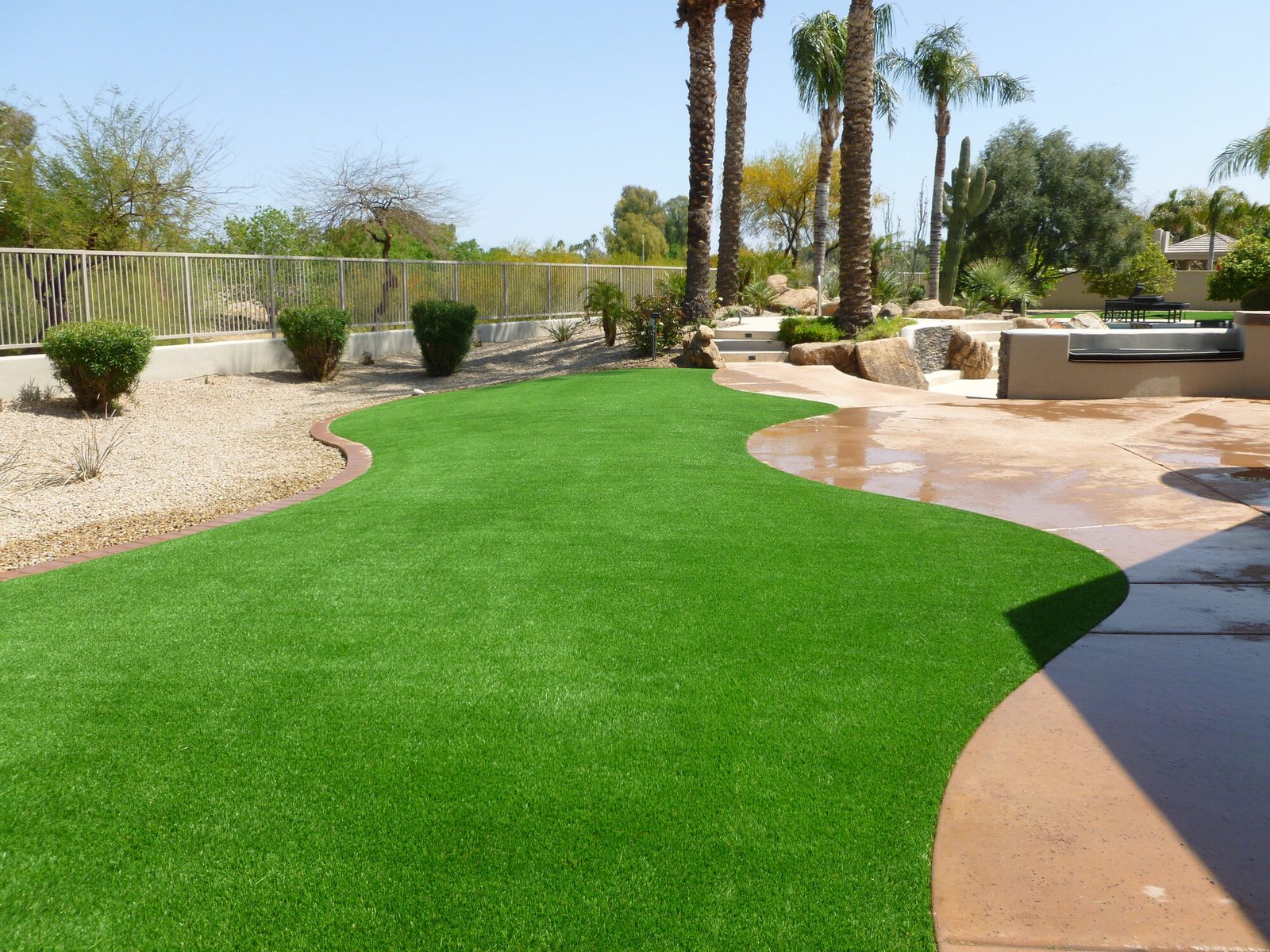 Curved turf lawn bordering a patio, installed by Arizona Turf Masters