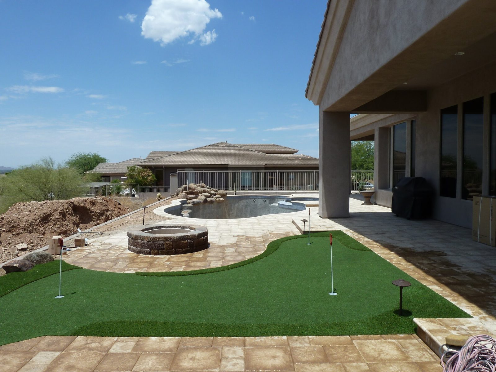 Putting green next to a fire pit and pavers, installed by Arizona Turf Masters