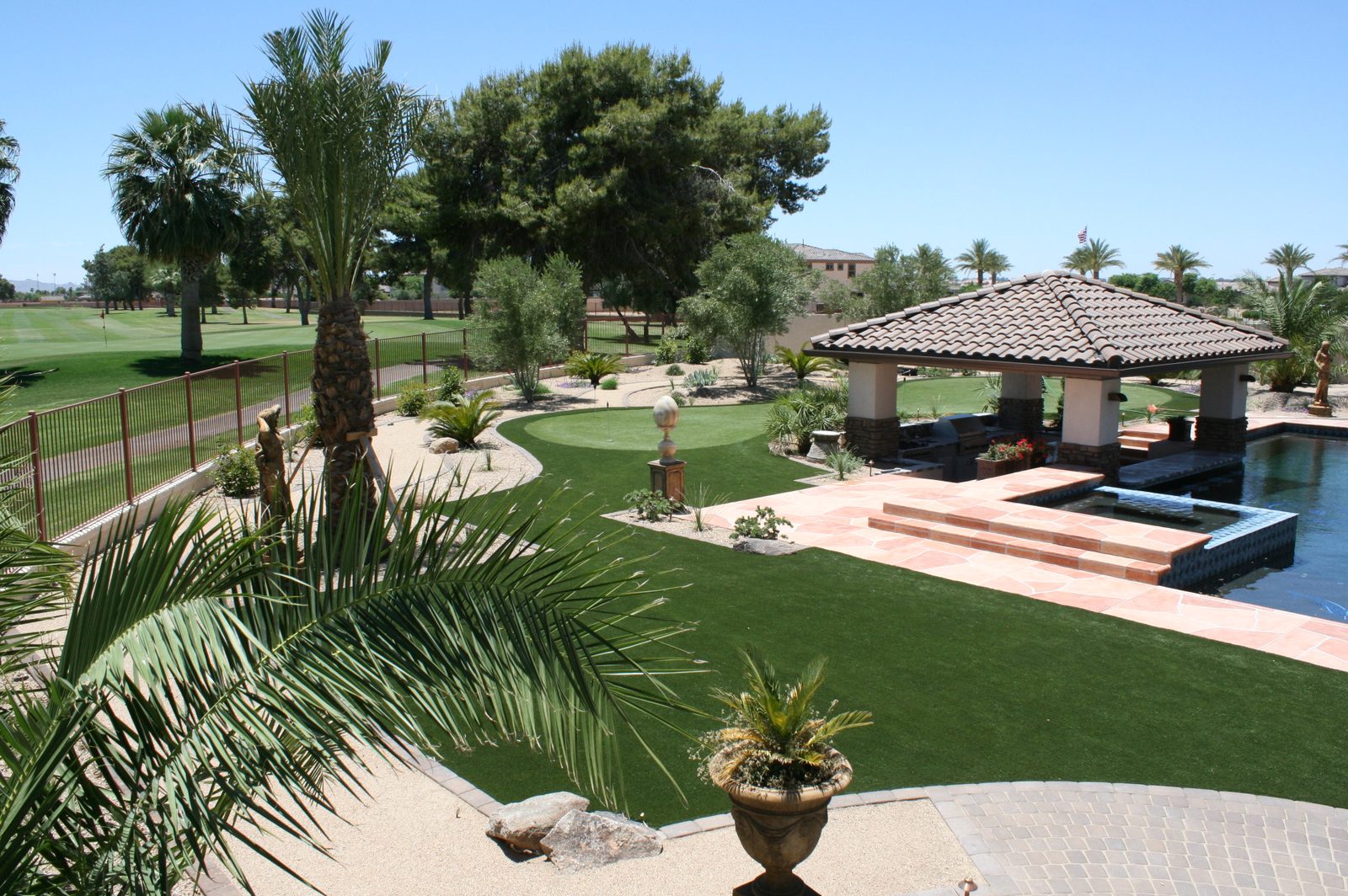 Backyard turf lawn and putting green beside a pool cabana, installed by Arizona Turf Masters