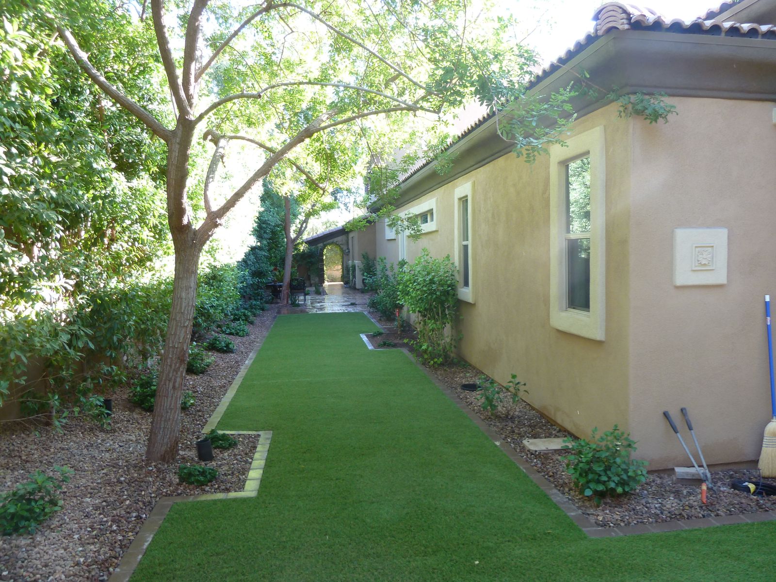 Narrow side-yard dog run with artificial turf running along a Phoenix home